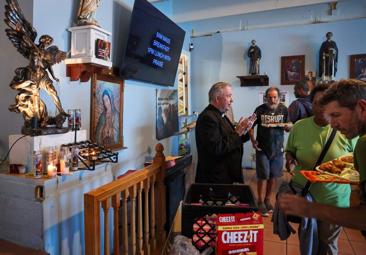 Father Bob Caudill, left, at All Saints Catholic Mission feeds the homeless as they line up for lunch despite city officials claiming it was against the rules on Monday, January 26, 2026, in Oakland Park, Florida. The city fined him $150 each day since 2016. He sued the city for religious discrimination. The trial was set to begin soon.