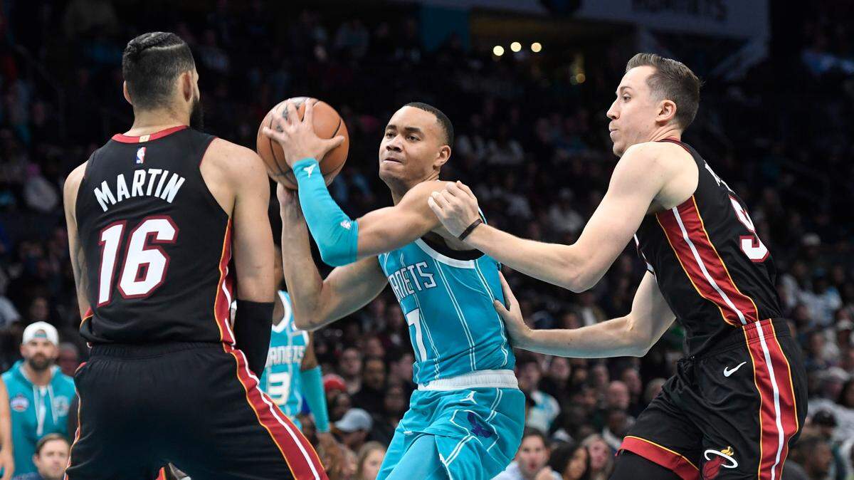 El guardia de Charlotte Hornets, Bryce McGowens (7), trata de evadir el marcaje de los delanteros del Heat Caleb Martin (16) y Duncan Robinson (55) este 11 de diciembre en el Spectrum Center.