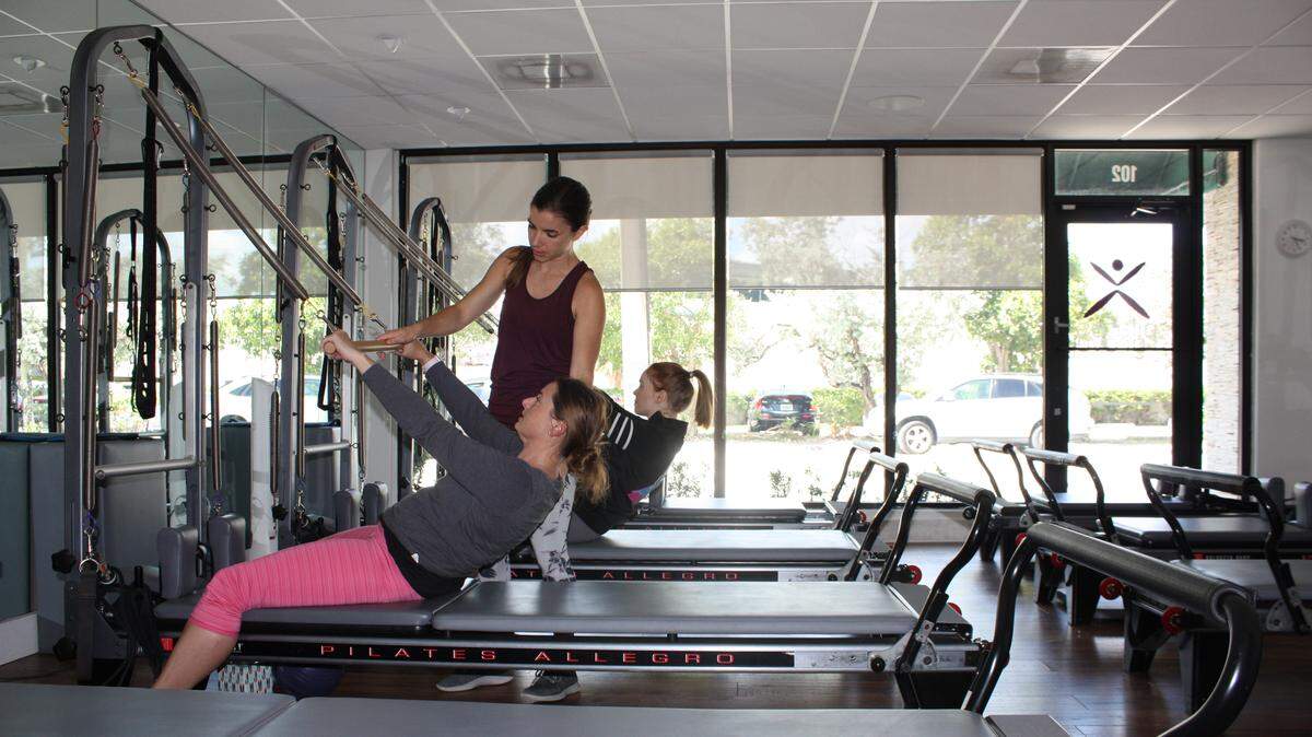 “Pilates for Neurological Conditions” instructor Kelsey Garcia assists class participants Mara Fowler, 40, and Caitlin Healy, 29, who both have multiple sclerosis. The next session starts Oct. 1.
