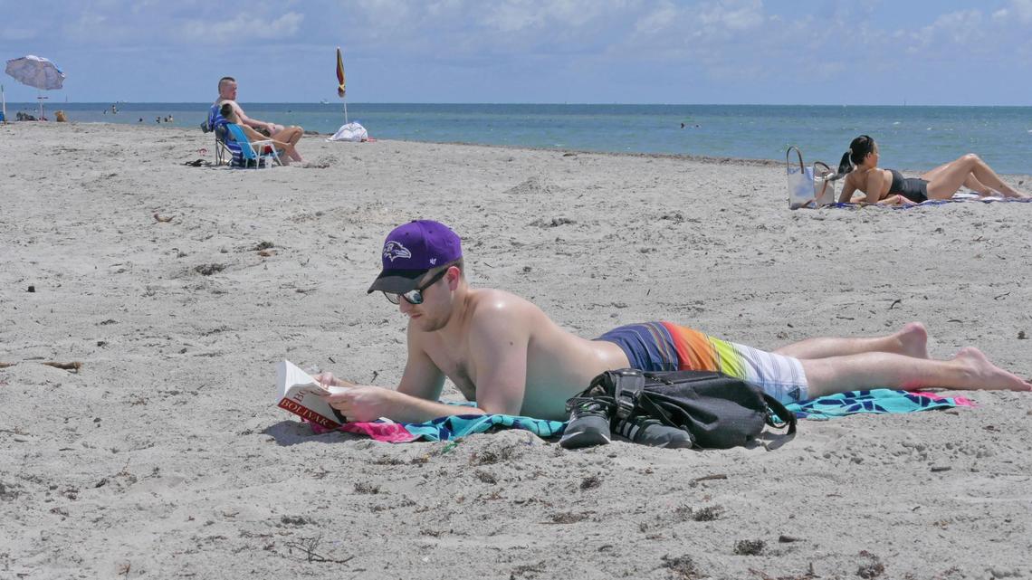 Jason Moeder, 25, of Brickell reads a book while sunbathing at Crandon Park’s southern beach.