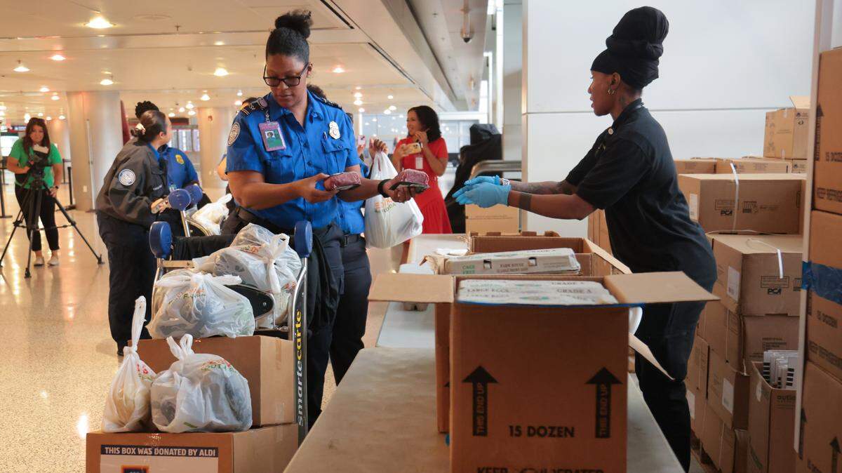 A Transportation Security Administration worker impacted by the federal government shutdown collects food items inside a luggage cart at Miami International Airport in Miami, Florida, Friday, October 24, 2025.
