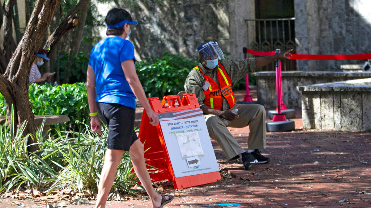 A polling worker directs a voter during the last day of early voting for the general elections at the Coral Gables Library on Sunday, November 1, 2020.