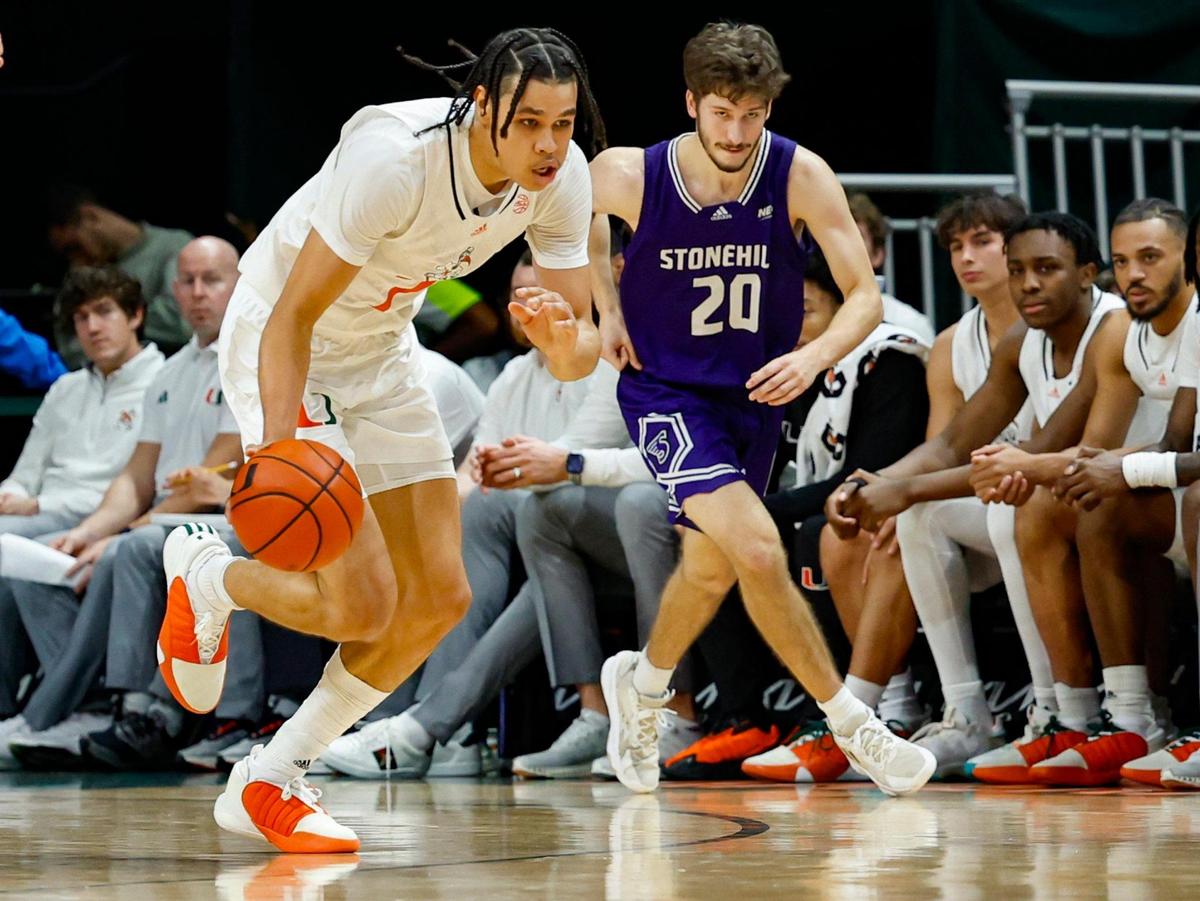 Miami Hurricanes guard Kyshawn George (7) drives the ball as Stonehill Skyhawks guard Nathan McGill (20) gives chase during the first half at the Watsco Center in Coral Gables, Florida on Thursday, December 21, 2023.