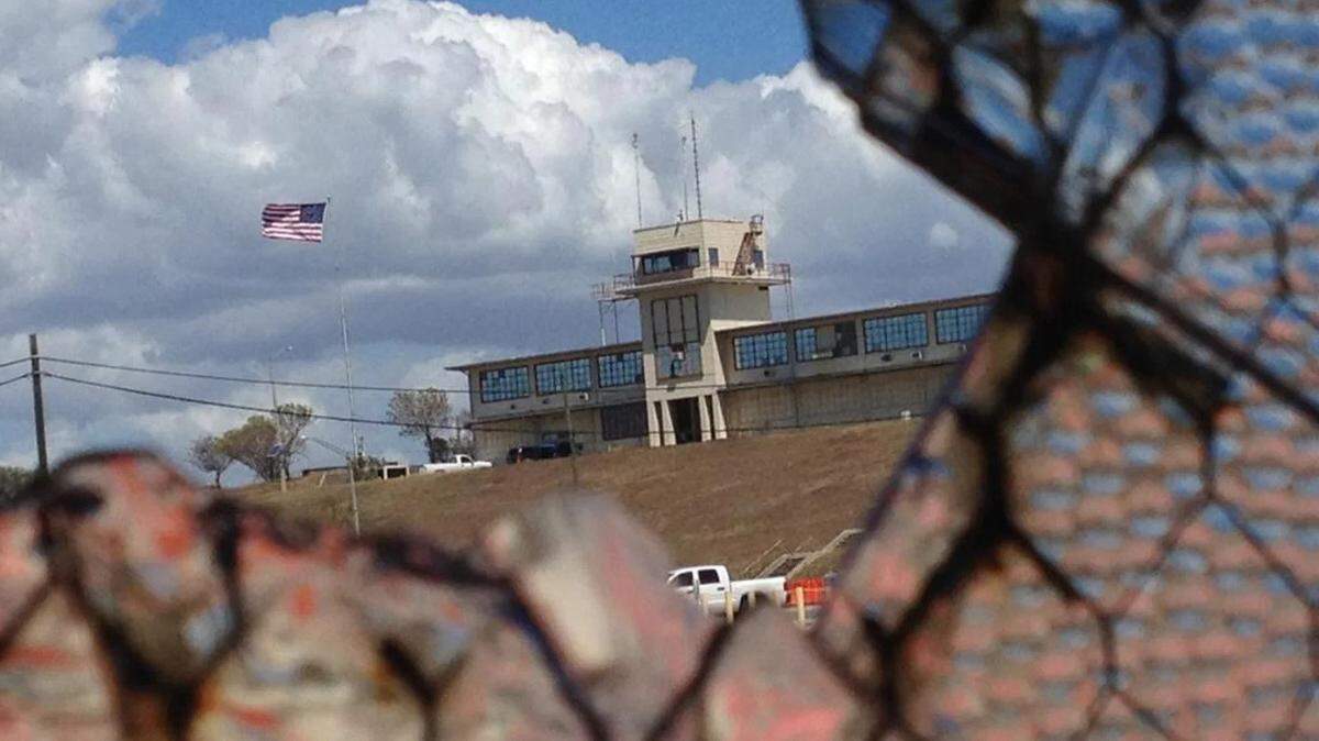 The war court headquarters at Camp Justice, at Guantánamo Bay, Cuba, seen through a broken window at an obsolete air hangar at the U.S. Navy base at Guantánamo Bay, Cuba.