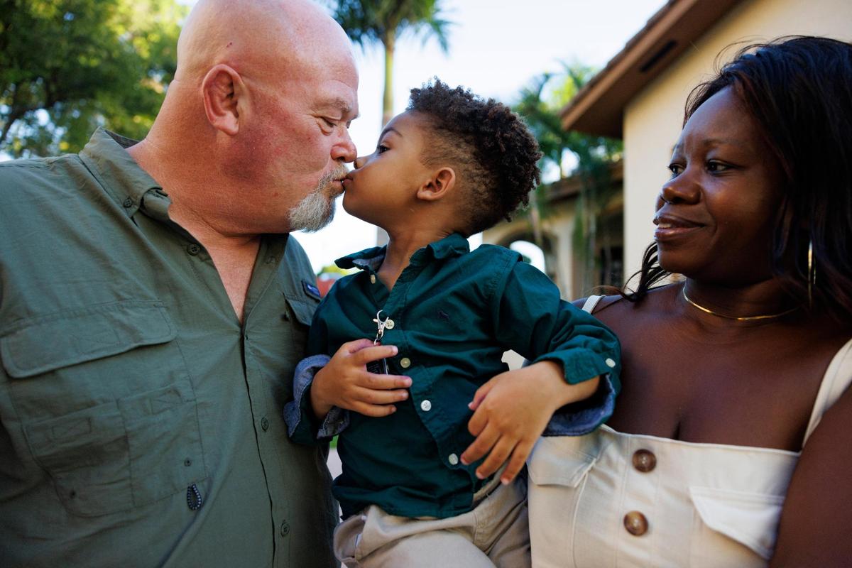 Ryan Hiott, left, kisses his son, Ryan Jr., center, who is held by his wife, Erica, on Wednesday, Oct. 23, 2024, in Miami.