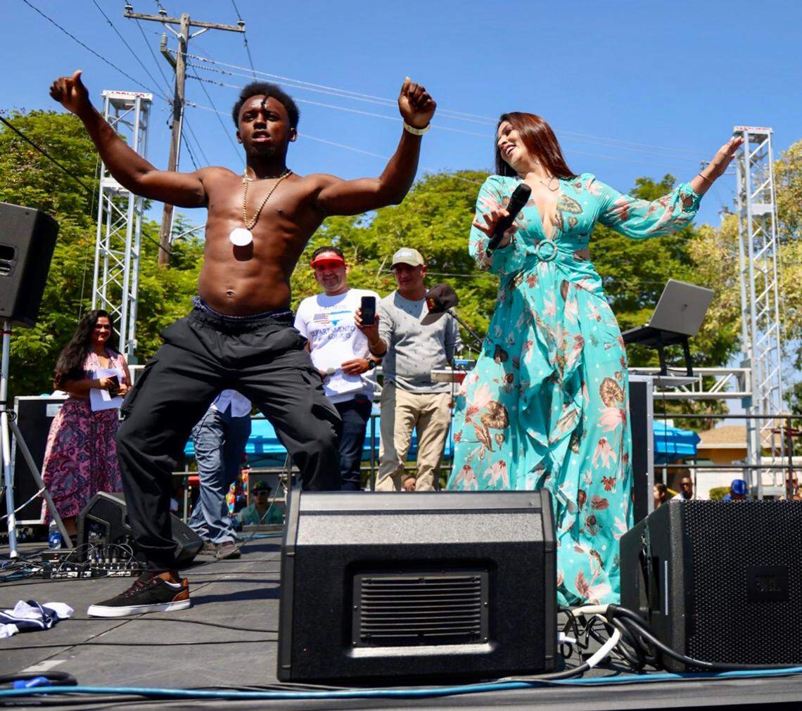 Festival attendee Brian Pastor, 23, left, steps up on stage for the dance challenge with Latin TV personality Carolina Lanza Navarro at the Central American stage during the Calle Ocho Festival on Sunday, March 12, 2023.