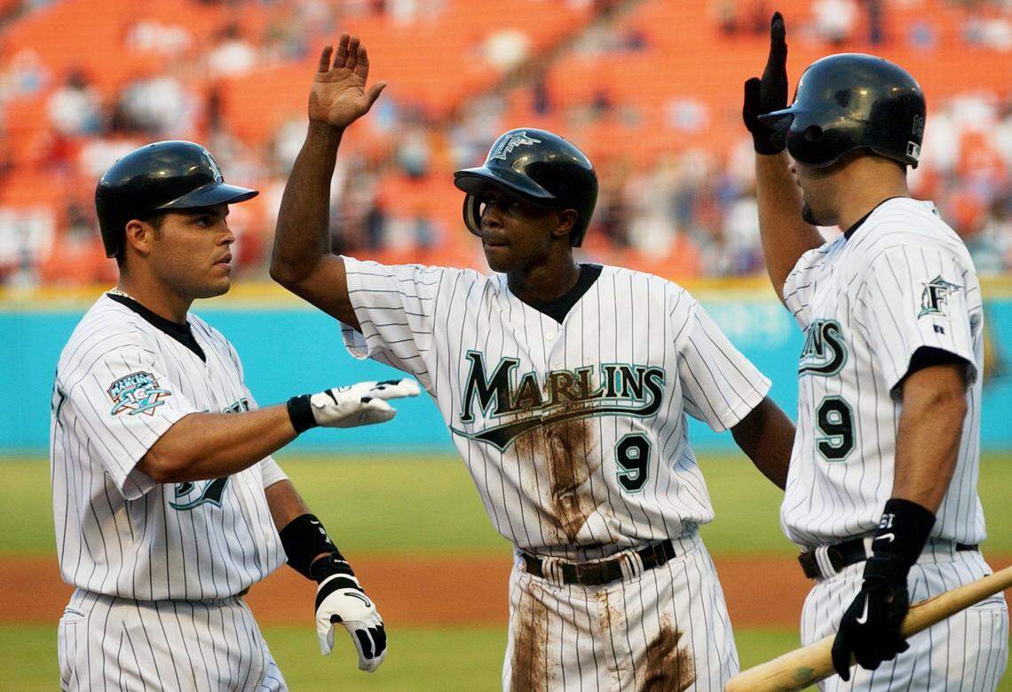 Florida Marlins' Ivan Rodriguez, left, is greeted by teammates Juan Pierre, center, and Mike Lowell, right, after hitting a three-run home run against Atlanta Braves pitcher Greg Maddux in the first inning Monday, June 30, 2003, in Miami.