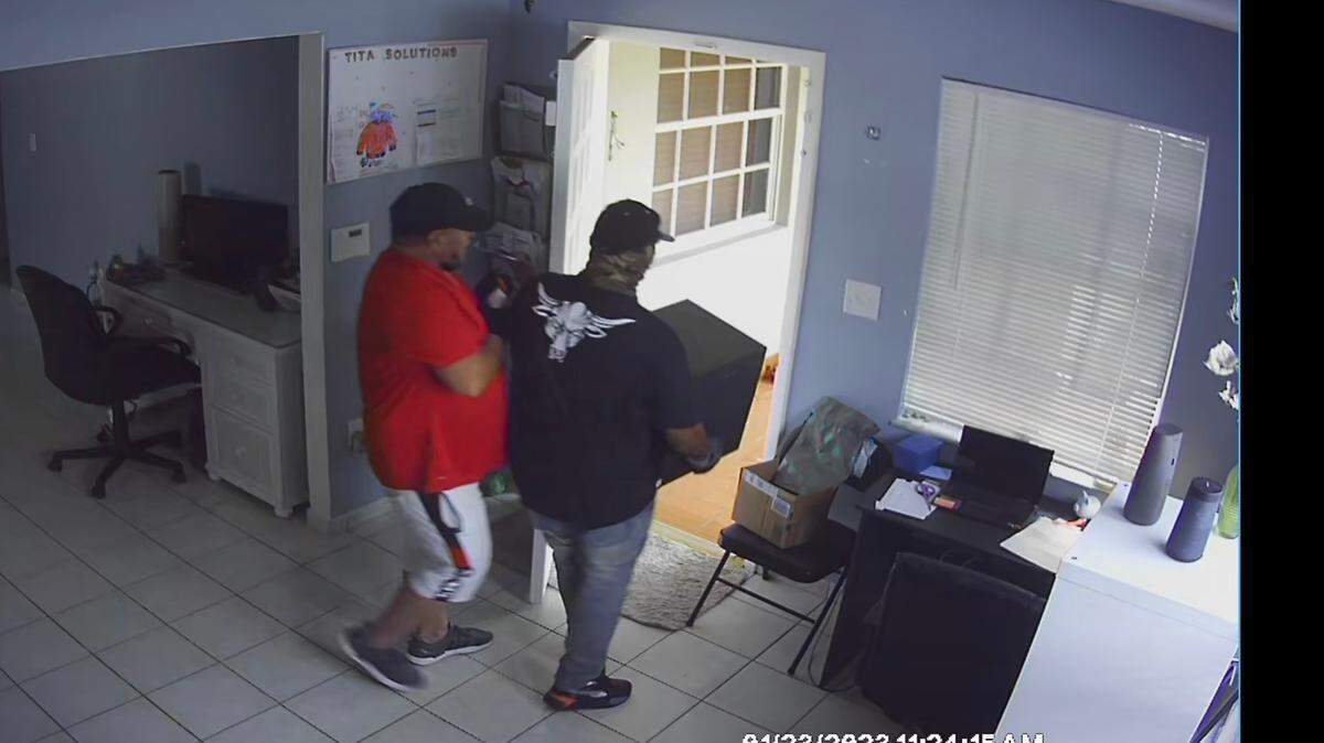 Two men are seen walking out of a city of Miami home carrying a safe on Monday, Jan. 23, 2023.