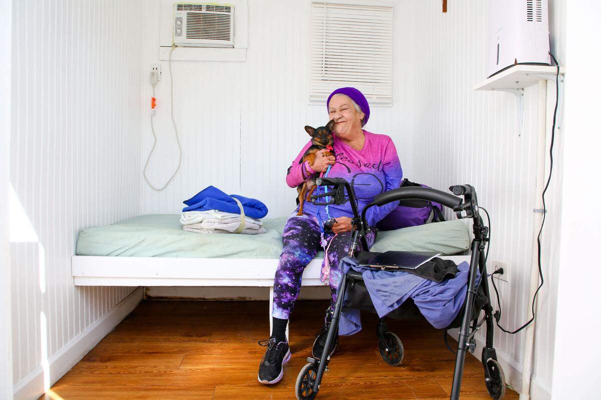 New Pinellas Hope resident Sandy Silvey visits with her chihuahua Bay Bay in her Hope Cottage on Tuesday, Feb 27, 2024, in Clearwater. Hope Cottages are 20-foot steel shipping containers that have been reconfigured to create 3 rooms in which residents live and that replace tents.