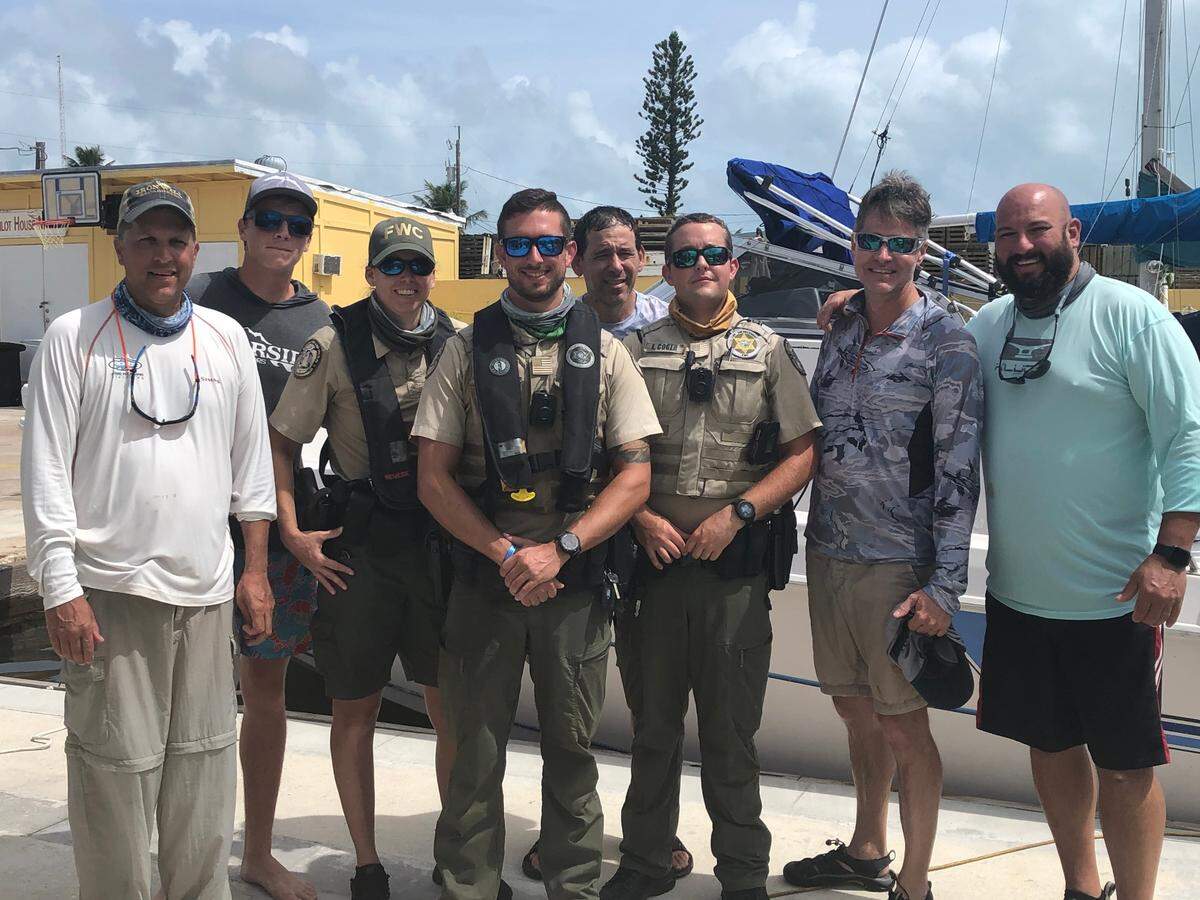 Florida Fish and Wildlife Conservation Commission officers stand with people they rescued from a sinking boat off Key Largo Monday, Oct. 5, 2020.