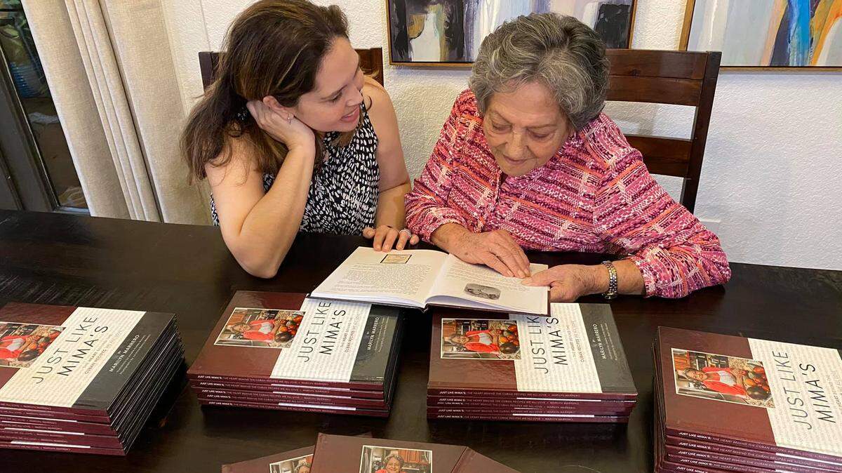 Marilyn Marrero and her maternal grandmother Cruz María Herrera “Mima” look over the new book of recipes from cooking in Cuba during the Revolution, and after in Miami.