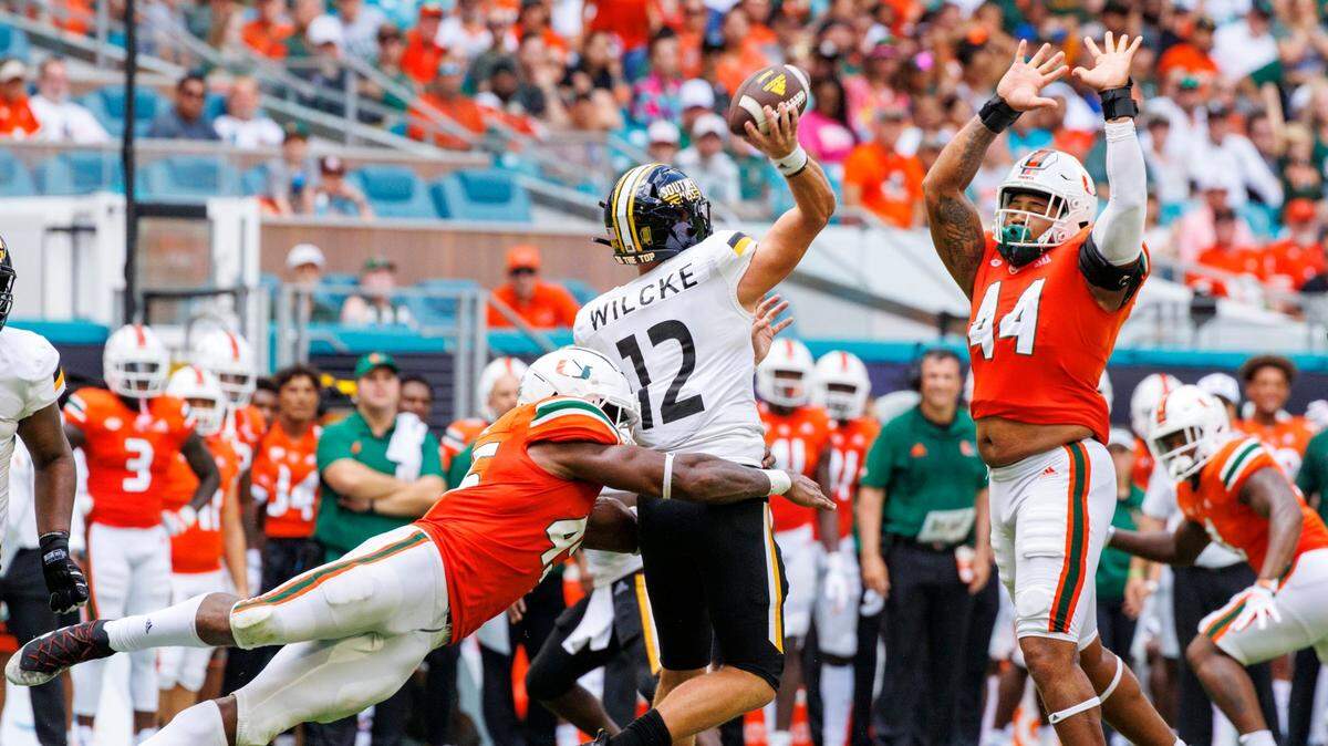 Southern Miss Golden Eagles quarterback Zach Wilcke (12) throws a pass against the pressure of Miami Hurricanes defensive lineman Mitchell Agude (45) and teammate Antonio Moultrie (44) during the second quarter of an NCAA non conference game at Hard Rock Stadium on Saturday, September 10, 2022 in Miami Gardens, Florida.