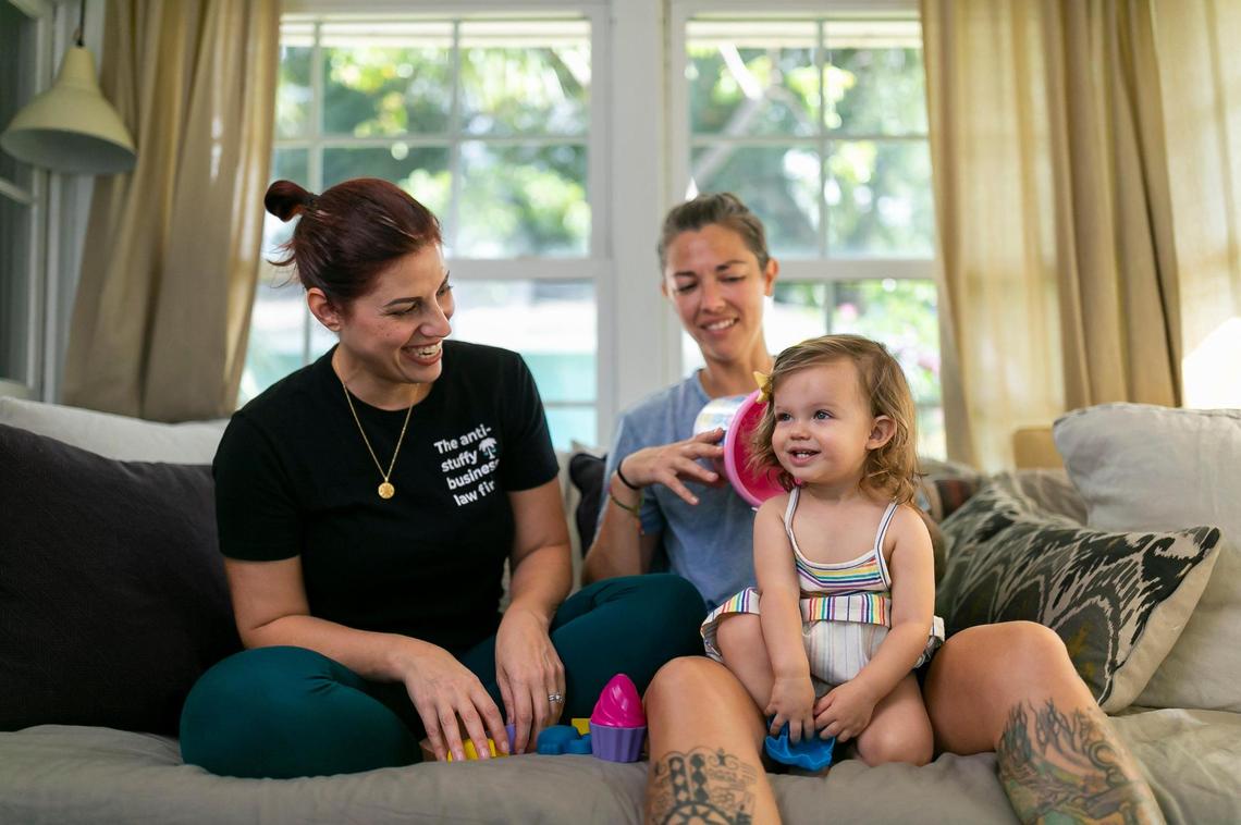 Broward Sheriff’s Office Battalion Chief Nichole Notte, 41, sits next to her wife, Michelle Notte, left, with their daughter, Luca, 1, at their home on Tuesday, June 21, 2022, in Fort Lauderdale, Fla. Nichole, who was a first responder during the Champlain Towers South condo collapse in Surfside, has been dealing with post traumatic stress disorder and anxiety.