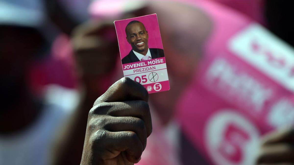 A protester&nbsp;holds a photo of presidential candidate Jovenel Moïse&nbsp;near the headquarters of the Provisional Electoral Council in Port-au-Prince last April, as demonstrators demanded that elections be held. Haiti’s tortuous election process dragged on for more than 14 months before Moise was declared the victor. 