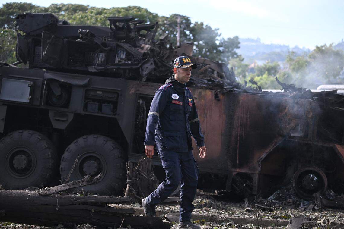 A firefighters passes by a burnt military vehicle at La Carlota air base in Caracas on January 3, 2026, after US forces captured Venezuelan leader Nicolas Maduro after launching a "large scale strike" on the South American country.