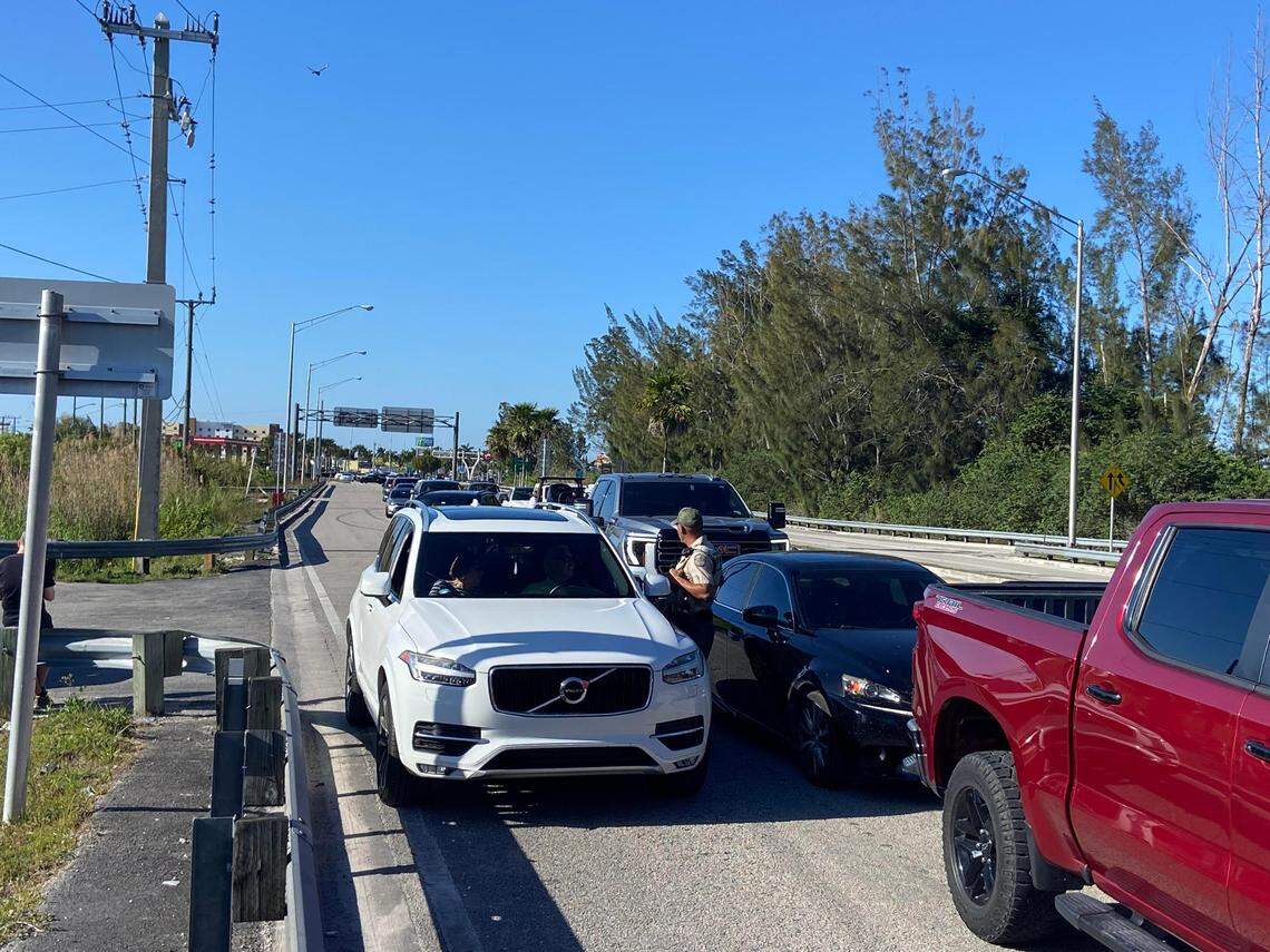 A Florida Fish and Wildlife Conservation Commission police officer speaks to stranded drivers stuck on U.S. 1 right before the 18 Mile Stretch, which was closed Tuesday, March 18, 2025, due to wildfires burning along the roadways to the Florida Keys.