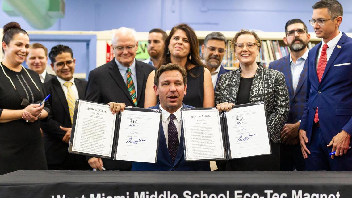 Governor Ron DeSantis holds up bills he signed revamping Florida’s literacy and early childhood learning, at West Miami Middle School in Miami on Tuesday, May 4, 2021.