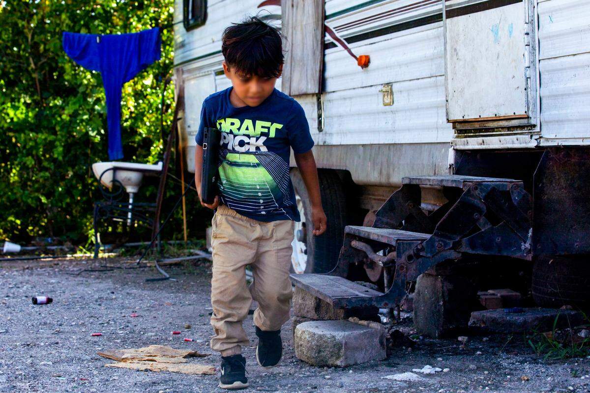 A young migrant boy exits his family’s trailer at the beckoning of a Miami-Dade County Public Schools employee who had taken a lead role on assisting the kids with virtual learning during the coronavirus pandemic in South Florida on Thursday, May 21, 2020.