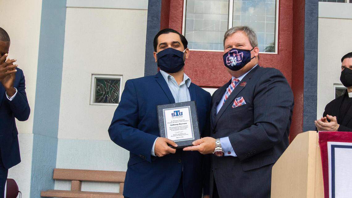 Former St. Thomas University student, Anthony Barroso, left, gets an award for his actions against anti-Semitism from President David A. Armstrong, J.D. at St. Thomas University in Miami Gardens on March 2, 2021.