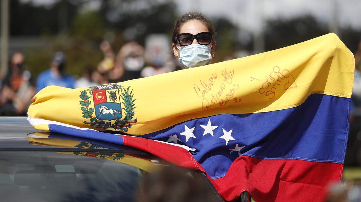 A woman with a Venezuelan flag cheers while former President Obama campaigns for candidate Joe Biden in Orlando last October.
