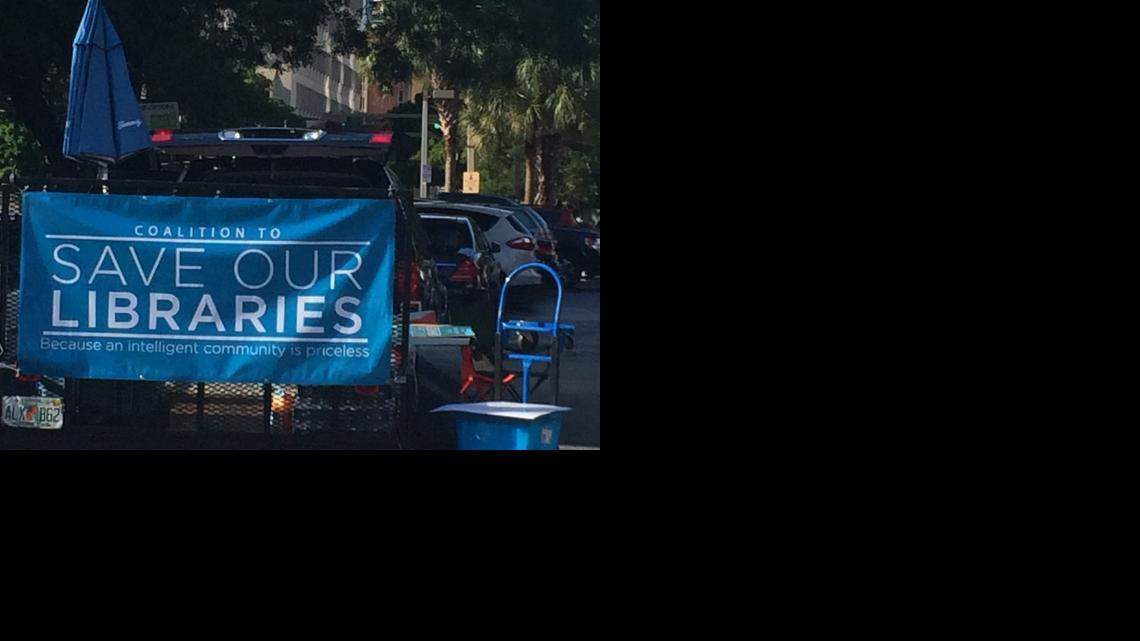 In the parking lot outside Miami-Dade County Hall, a banner for the Coalition to Save Our Libraries reads, “Save our libraries because an intelligent community is priceless.”