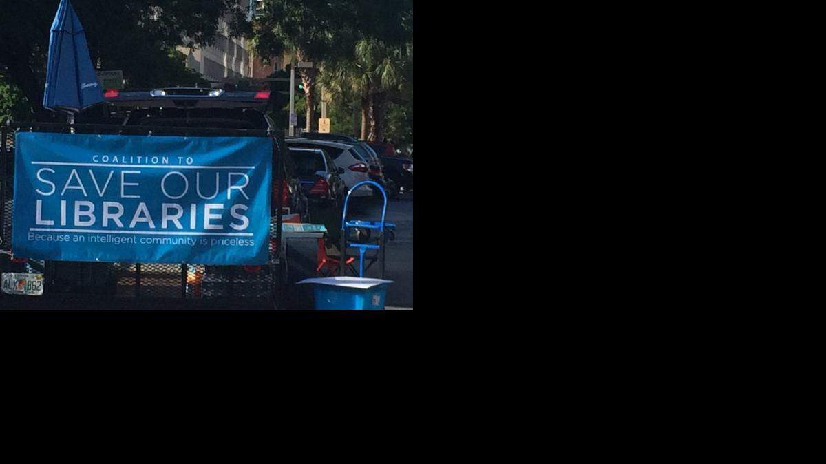 In the parking lot outside Miami-Dade County Hall, a banner for the Coalition to Save Our Libraries reads, “Save our libraries because an intelligent community is priceless.”
