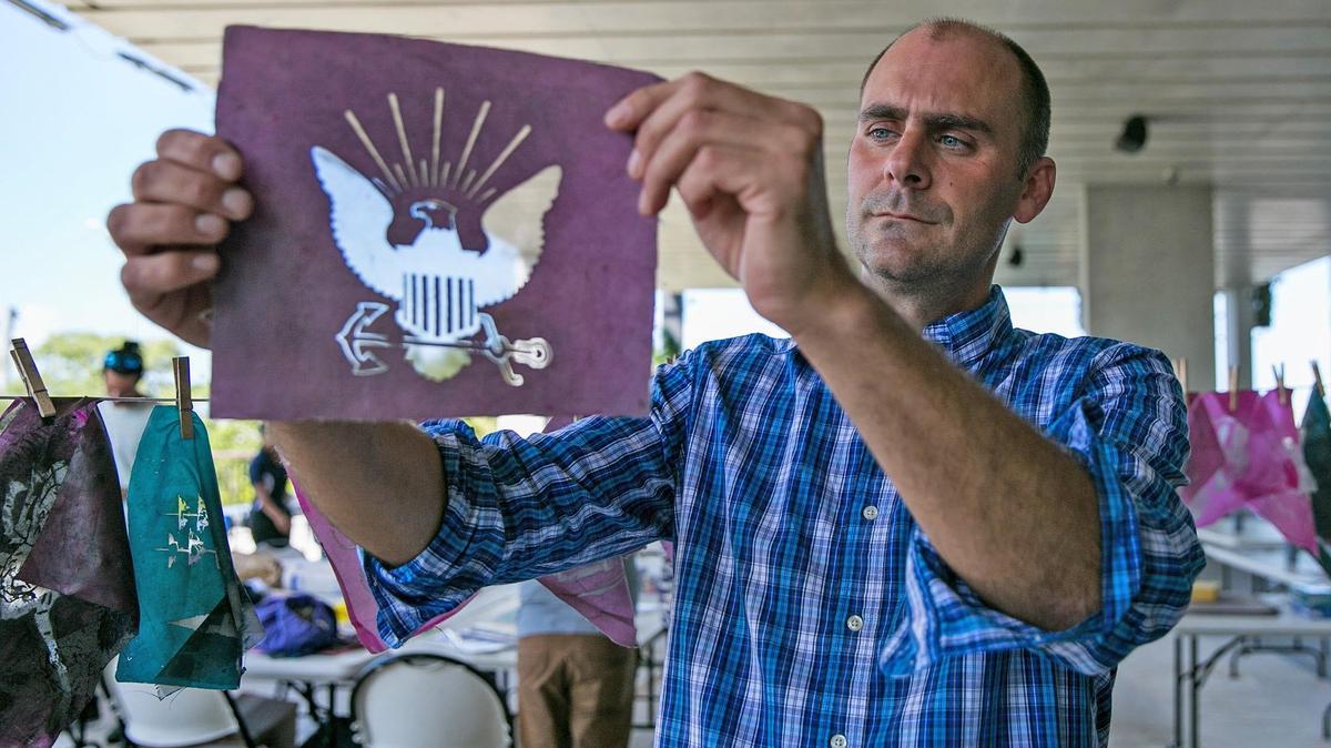 Drew Matott, Director of the Peace Paper Projects inspects one of the silkscreens stencils produced by Miami-Dade County veterans in his class at the PAMM in Miami on Thursday, August 2, 2018