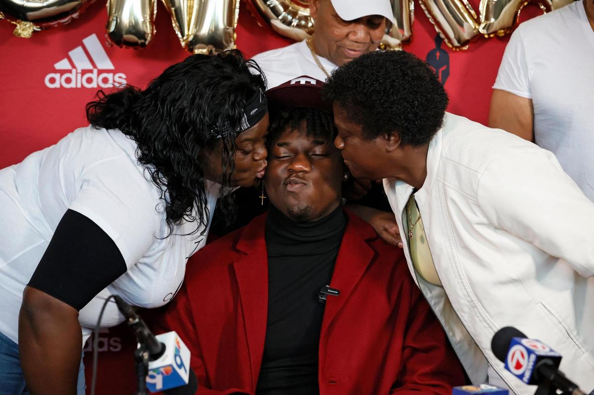 Latoya Smith, mother and Margaret Sterling, grandmother kiss Monsignor Edward Pace defensive end Shemar Stewart after choosing to sign with Texas A&M University football during National Signing Day at Monsignor Edward Pace High School in Miami Gardens, Florida, on Wednesday, February 2, 2022.