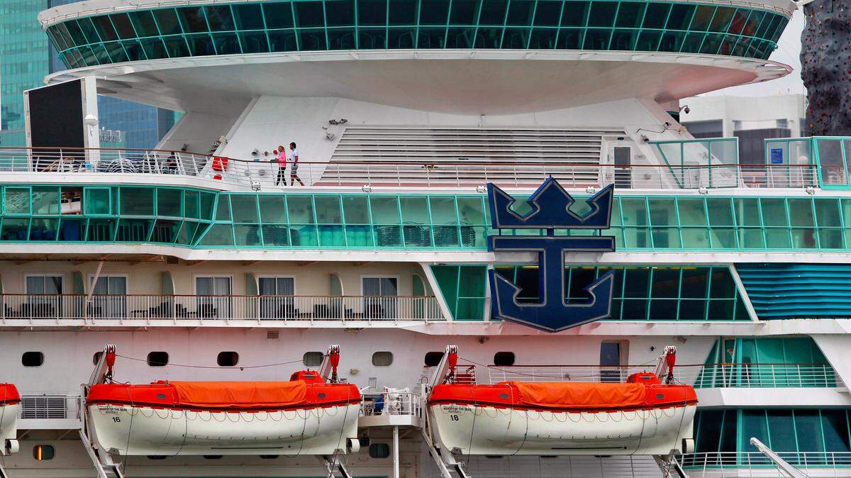 Under gray skies crew members walk the upper deck of Royal Caribbean’s Majesty of the Seas cruise ship docked at PortMiami on Thursday, May 14, 2020.