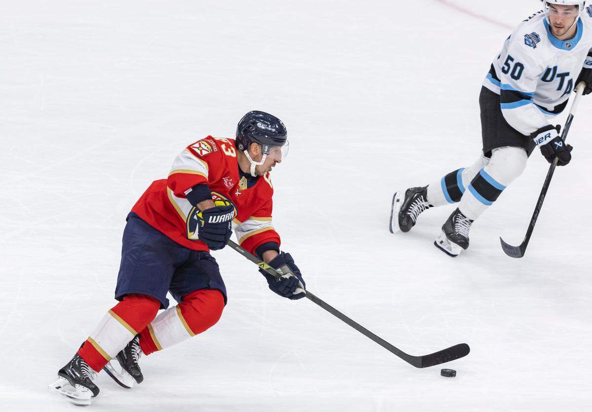 Florida Panthers center Brad Marchand (63) skates with the puck as Utah Hockey Club defenseman Sean Durzi (50) defends in the overtime period of their NHL game at Amerant Bank Arena on Friday, March 28, 2025, in Sunrise, Fla.