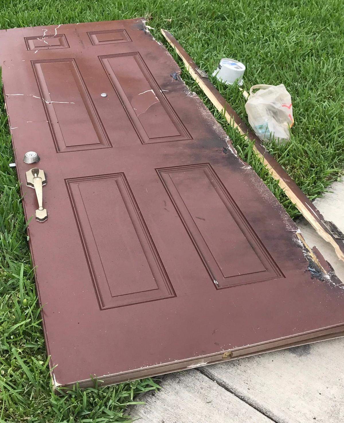 A broken door rests in the grass across the street from a townhome on SW 117th Court Monday, Sept. 10. 2018, where a man fatally shot a woman, then himself.