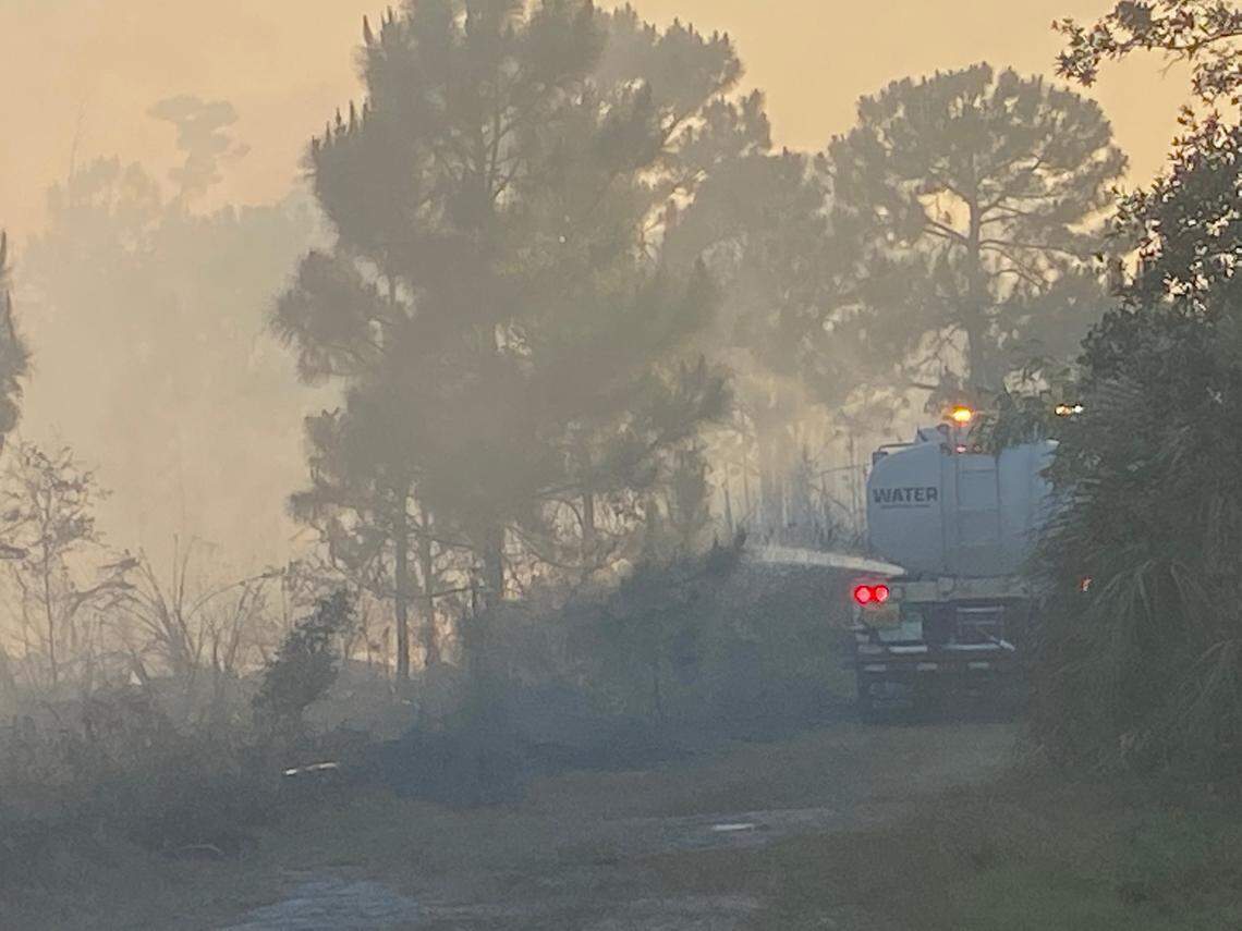A Miami-Dade County water truck sprays down flames to keep a prescribed burn under control on SW 152nd Street in Palmetto Bay Wednesday, May 3, 2023.
