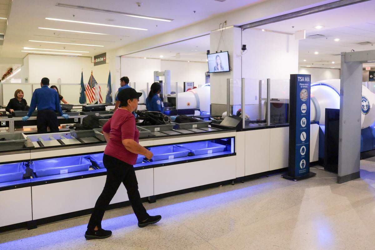 A traveler walks toward a metal detector after placing her luggage and personal belongings inside a bin on a lane with an automated bin return system during a standard security screening at checkpoint 2 at Miami International Airport on Tuesday, Nov. 25, in Miami, Fla.