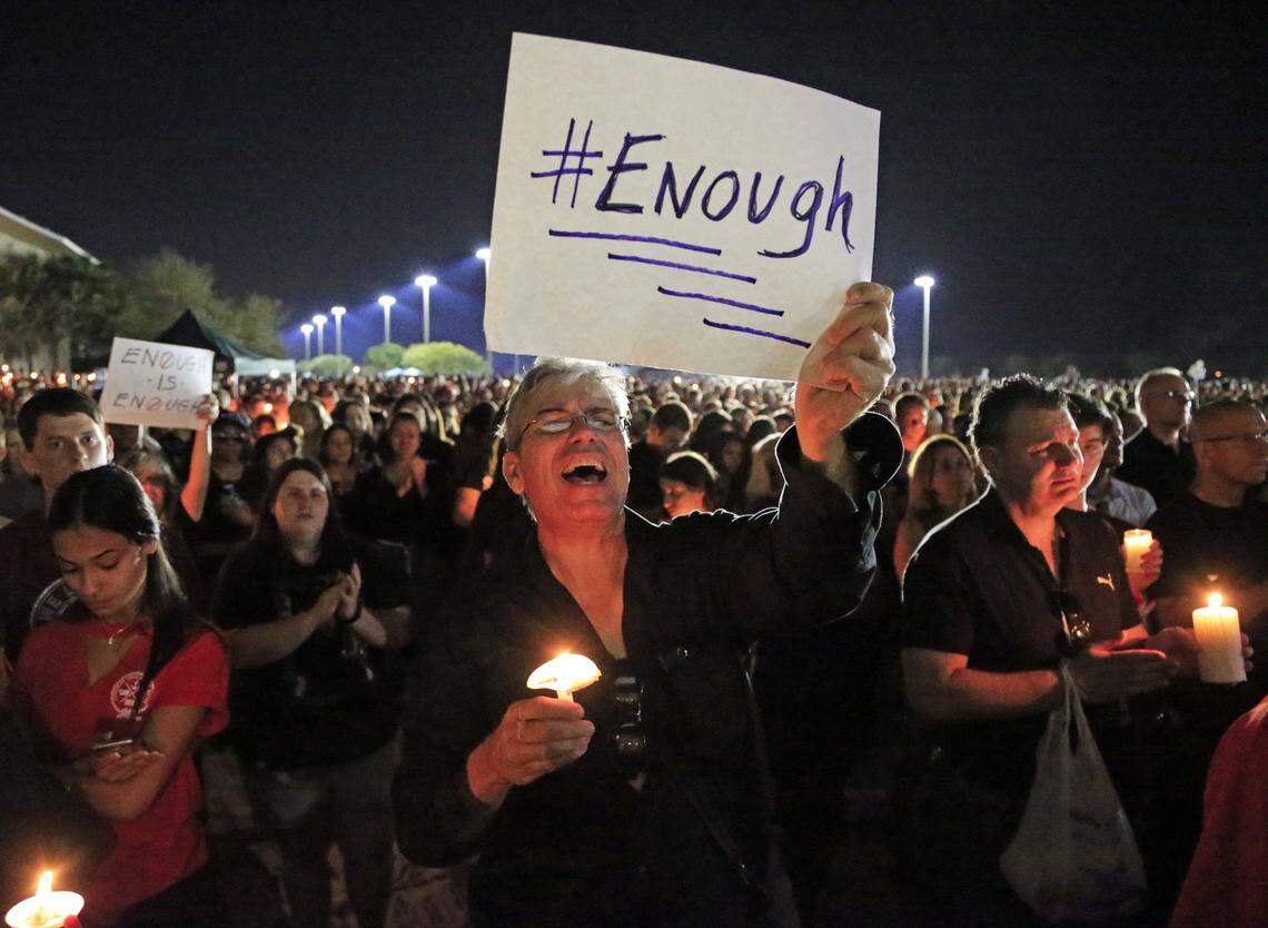 Mark Rodriguez holds a sign with #enough during a candlelight vigil at Pines Trails Park & Amphitheater for shooting victims from Marjory Stoneman Douglas High School on Tuesday, February 15, 2018.