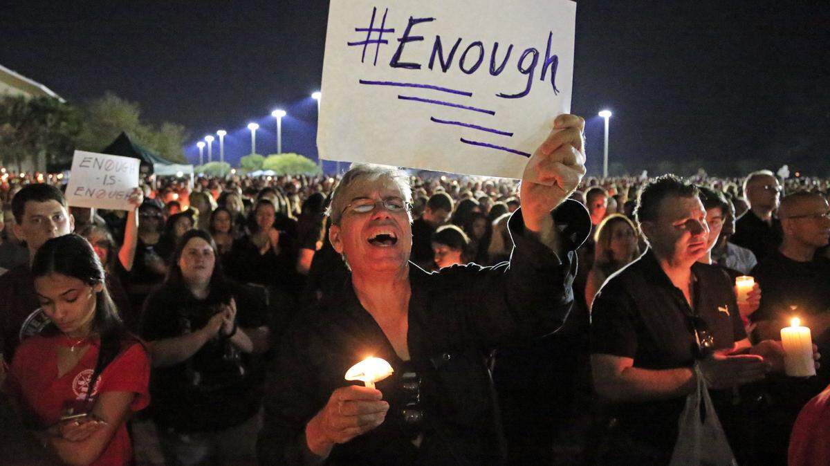 Mark Rodriguez holds a sign with #enough during a candlelight vigil at Pines Trails Park & Amphitheater for shooting victims from Marjory Stoneman Douglas High School on Tuesday, February 15, 2018.