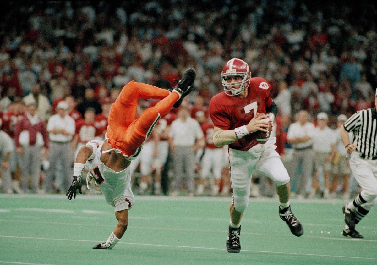 Alabama quarterback Jay Barker (7) runs around University of Miami linebacker Rohan Marley, left, who was flipped up in the air by Alabama’s Derrick Lassic (not shown) during the second quarter of the Sugar Bowl at the Superdome in New Orleans, La., Jan. 1, 1993. (AP Photo/Bill Feig)