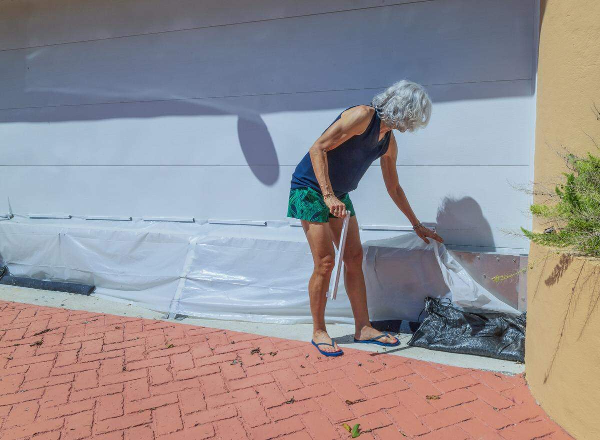 Terri K. Echarte uncovers an aluminum barrier used at her house garage door to avoid the water from coming inside, whenever her street gets flooded, In Miami Beach, on Wednesday, September 10, 2025.