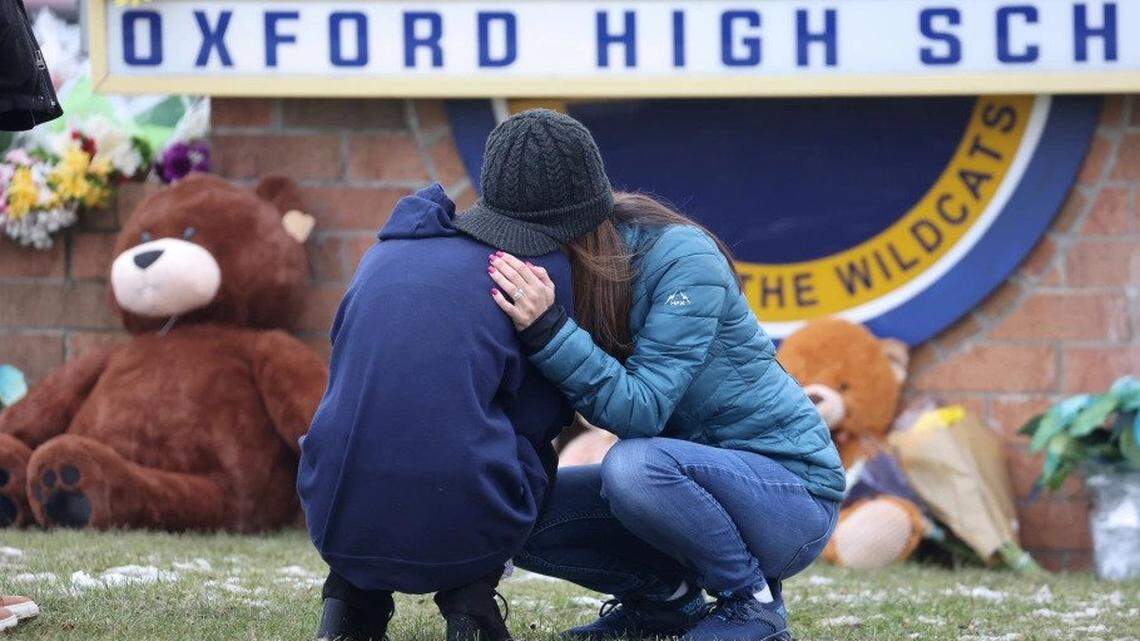 Two people embrace at a makeshift memorial outside of Oxford High School where four students were killed.