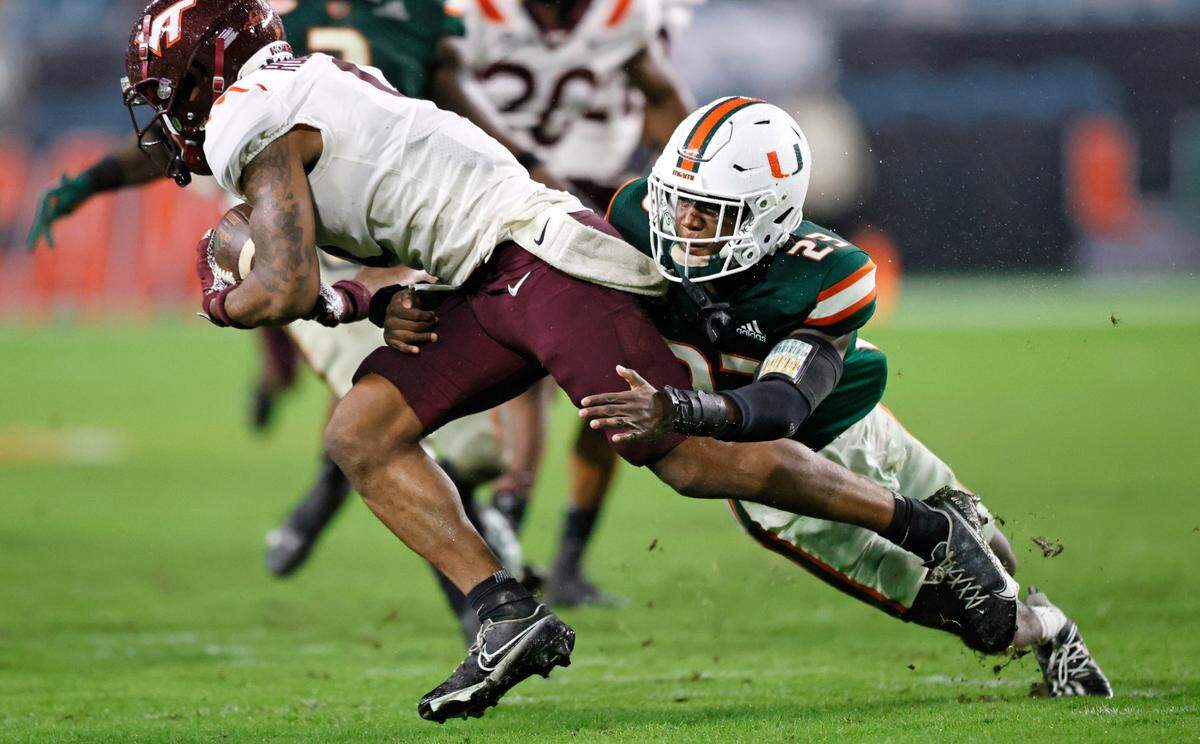 Miami Hurricanes cornerback Te’Cory Couch (23) tackle Virginia Tech Hokies wide receiver Tayvion Robinson (9) during the fourth quarter of their ACC football game at Hard Rock Stadium on Saturday, November 20, 2021 in Miami Gardens, Florida.