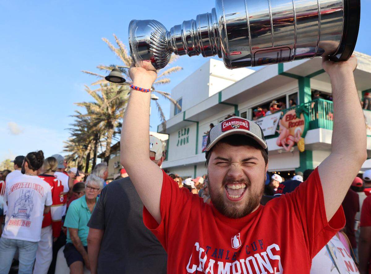 Panthers fan Anthony Valentino, 24, raises his personal trophy in celebration of the Stanley Cup win outside the Elbo Room in Fort Lauderdale at sunrise the day after the Florida Panthers won the Stanley Cup Final for the second time on Wednesday, June 18, 2025.