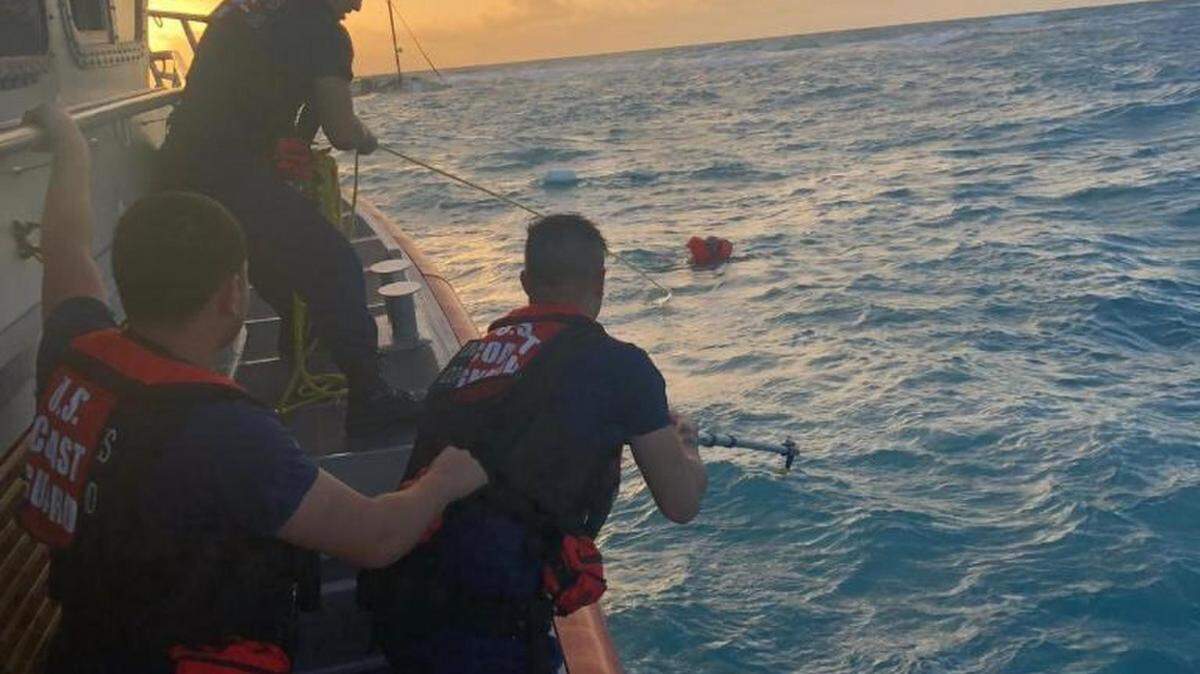 A Coast Guard Station Islamorada 45-foot Response Boat-Medium crew pulls a man towards towards the boat near Key Largo, Feb. 21, 2019. After receiving a distress call from the crew of the sailing vessel, No Worries, stating they were taking on water, watchstanders launched the smallboat crew and a Coast Guard Air Station Miami MH-65 helicopter crew to the scene to assist.