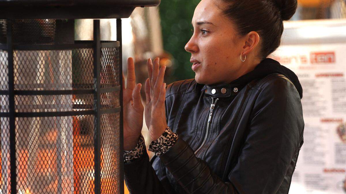 Ocean’s Ten hostess Gabriela Barrios, 25, tries to keep warm via space heater outside the South Beach restaurant as cool morning temperature moved through South Florida.