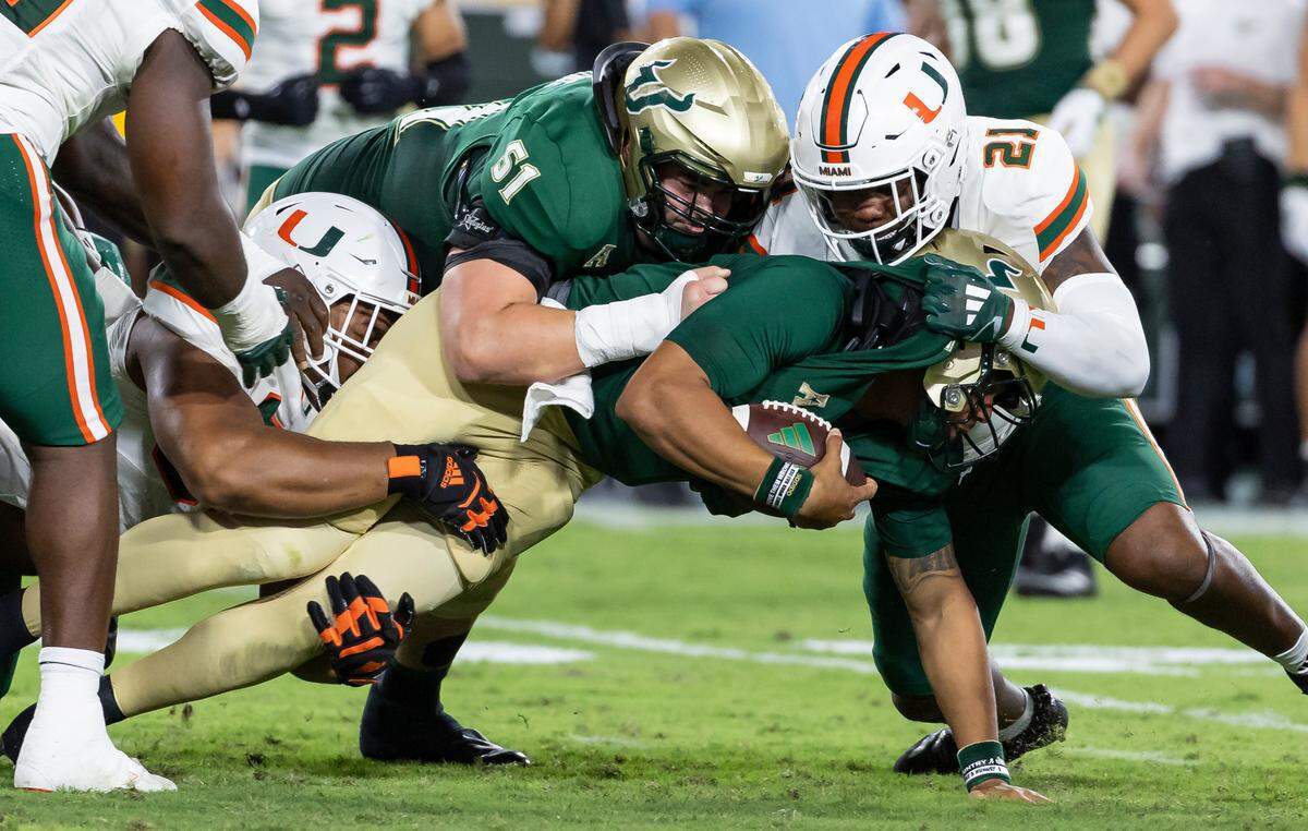 Miami Hurricanes linebacker Jaylin Alderman (21) works to stop South Florida Bulls quarterback Byrum Brown (17) in the first half of their NCAA college football game at the Raymond James Stadium on Saturday, Sept. 21, 2024, in Tampa, Fla.