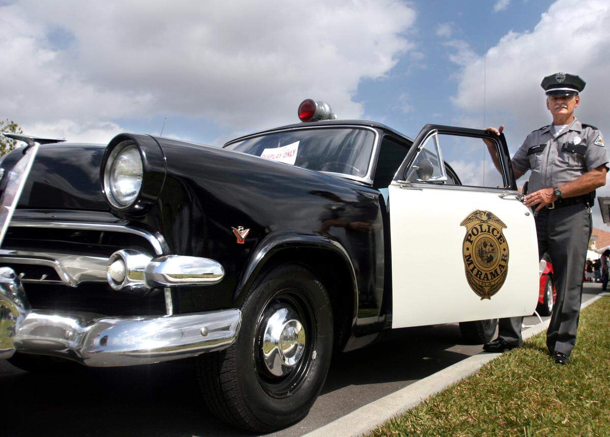 In 2007, Miramar Police Officer Bernard Bomba poses next to a real 1954 police car wearing an authentic Miramar police uniform from 1955.