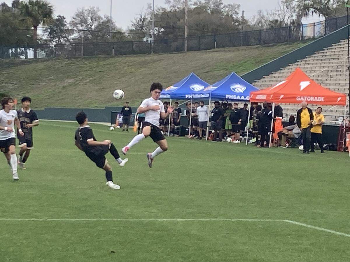 American Heritage’s Sebastian Mayorga (leaping) goes airborne chasing a 50-50 ball against Orlando Bishop Moore’ Sebastian Oliver during Saturday's Class 4A boys’ soccer final at Spec Martin Stadium in DeLand, Fla.