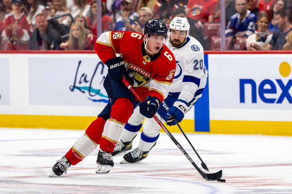 Florida Panthers defender Mike Reilly (6) skates with the puck as he is chased by Tampa Bay Lightning left wing Nicholas Paul (20) during the first period of an NHL game at Amerant Bank Arena in Sunrise, Florida, on Saturday, October 7, 2023.