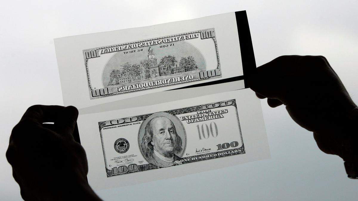 In this photo, a police investigator holds negatives of a hundred dollar bill used to print fake dollars in Cali, Colombia, Thursday, July 10, 2008. A New Jersey man was sentenced to five years in prison after creating counterfeit money with bleach, $1 bills and a printer, officials said. Fake $100’s were made.