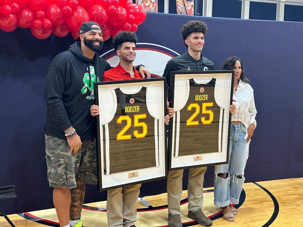 Columbus High basketball stars Cayden Boozer (red shirt) and Cameron Boozer (blue shirt) accept their McDonald’s All-American Game jerseys on Friday at the Explorers’ gym while joined by their father, Carlos (left), and mother, CeCe (right).