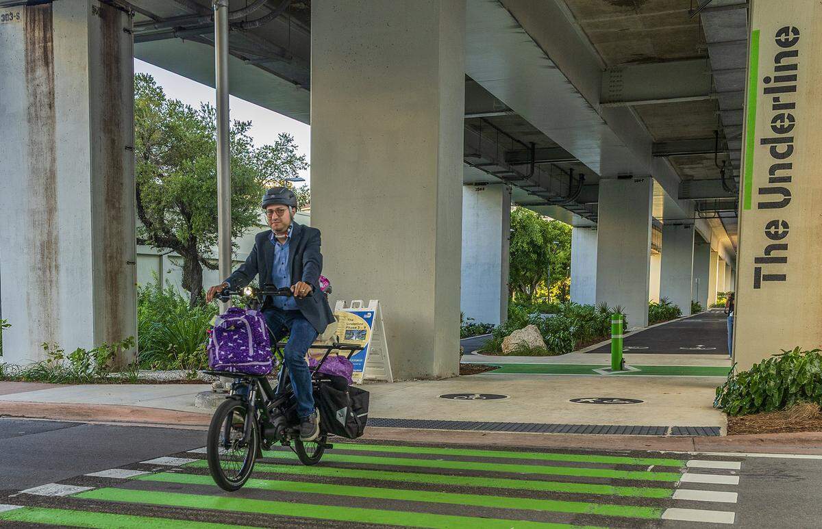 Kenneth Garcia takes his daughter to school riding his bike through The Underline in Coral Gables before heading to his work, since his family doesn't own a car, on Friday October 31, 2025.