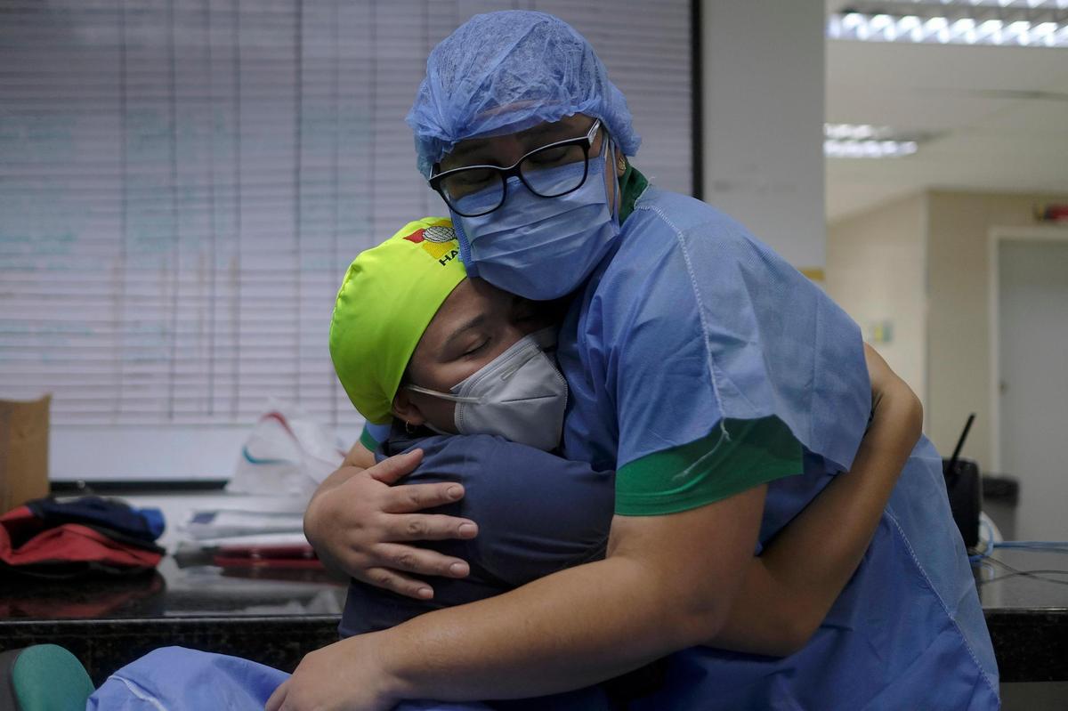 Health workers of the COVID-19 area embrace at the end of their shift at the Ana Francisca Pérez de León II public Hospital in Caracas, Venezuela, on March 23, 2021.